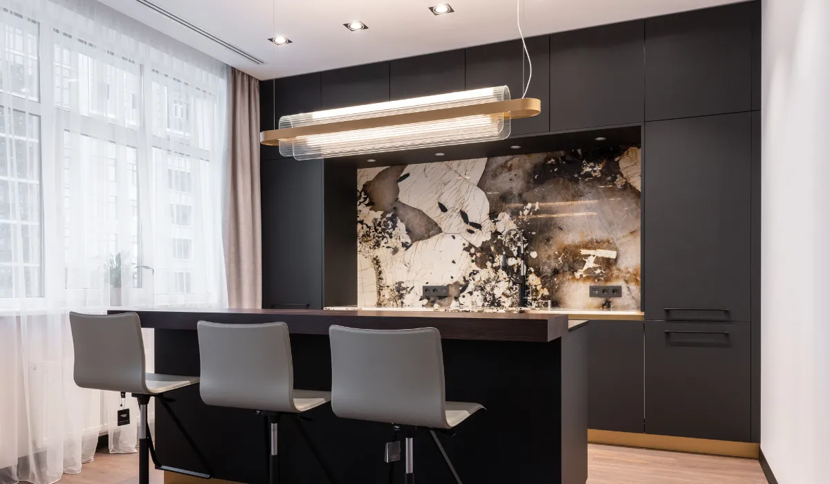 Modern kitchen lighting with sleek pendant fixture over a dark island countertop.