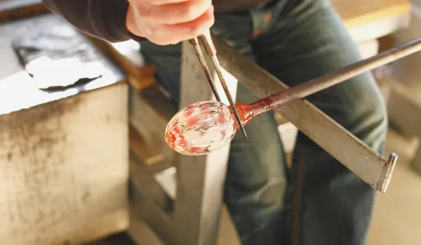 Skilled artisan shaping molten glass for unique, handcrafted lighting.
