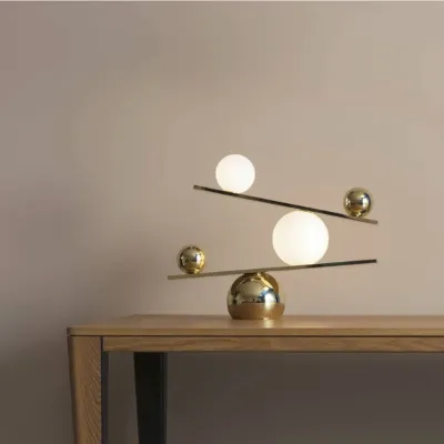 Modern balance table lamp with brass and frosted glass orbs, creating a sculptural lighting statement.