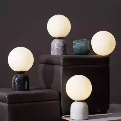 Modern marble table lamps with frosted glass globes, featuring unique sculptural designs in various shades.