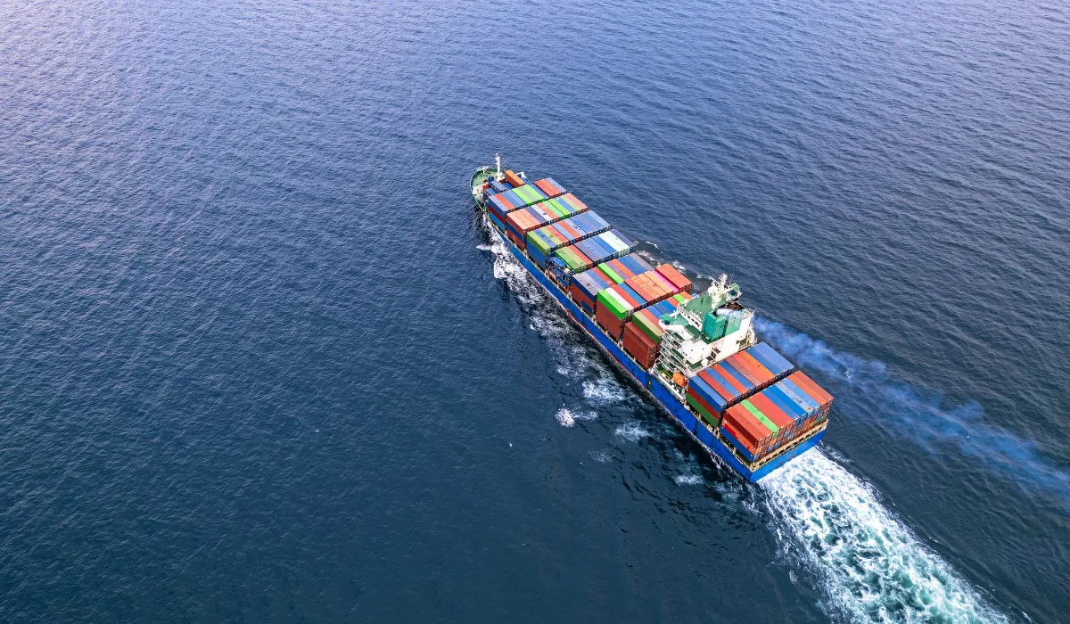 Aerial view of a cargo ship carrying colorful shipping containers across the ocean.