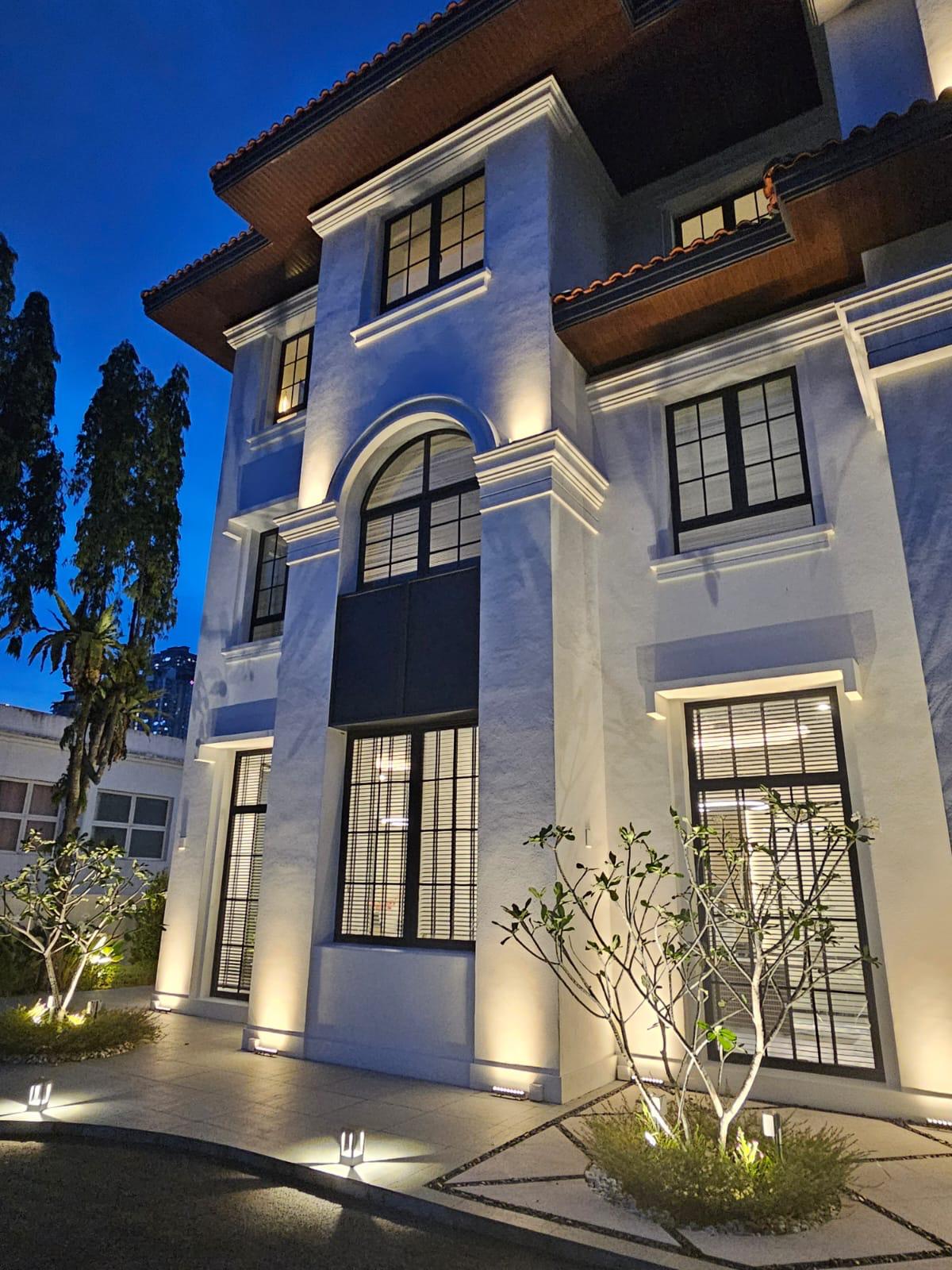 Three-storey residence with symmetrical façade and warm exterior lighting.