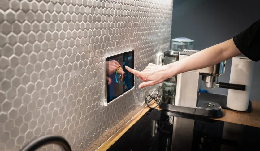 Person using a smart lighting control panel on a kitchen wall