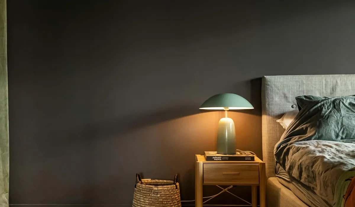 Modern bedside lamp on a nightstand with warm lighting, ideal for glare-free reading and creating a cozy bedroom atmosphere.