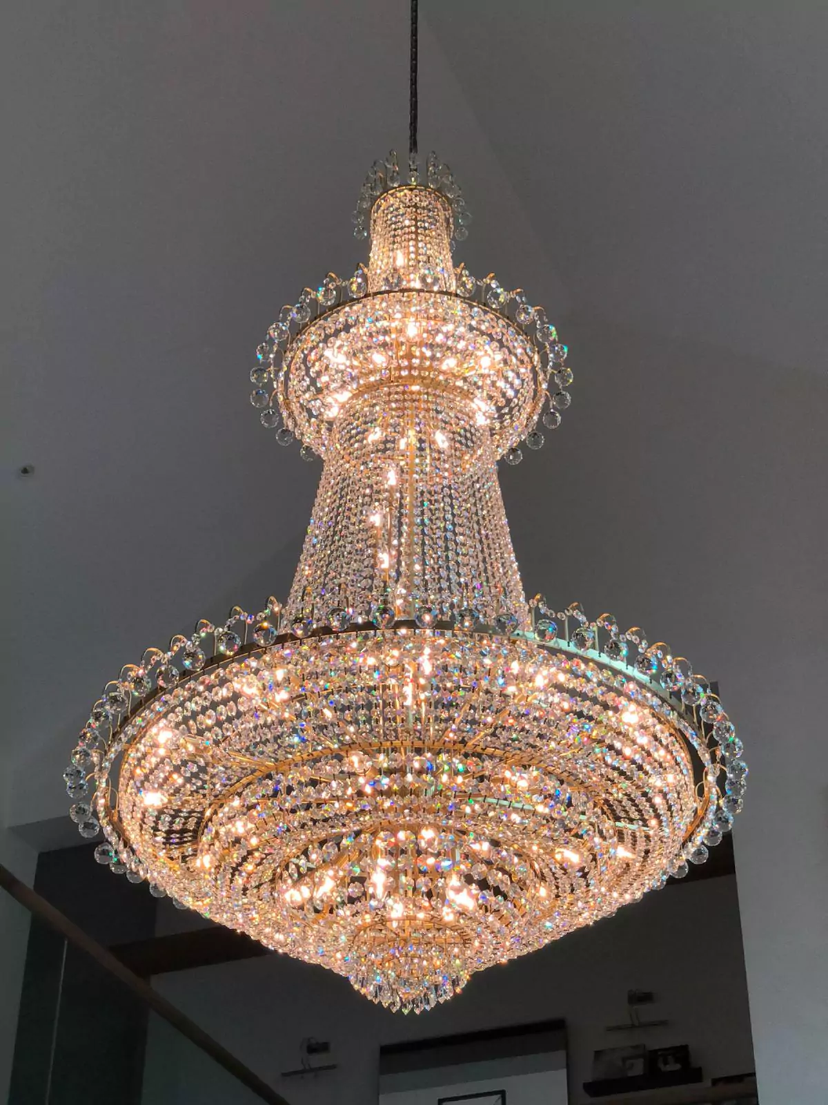 {"default":"Exquisite crystal chandelier restored to its original splendor, featuring multiple tiers of shimmering crystals that create a dazzling light display."}