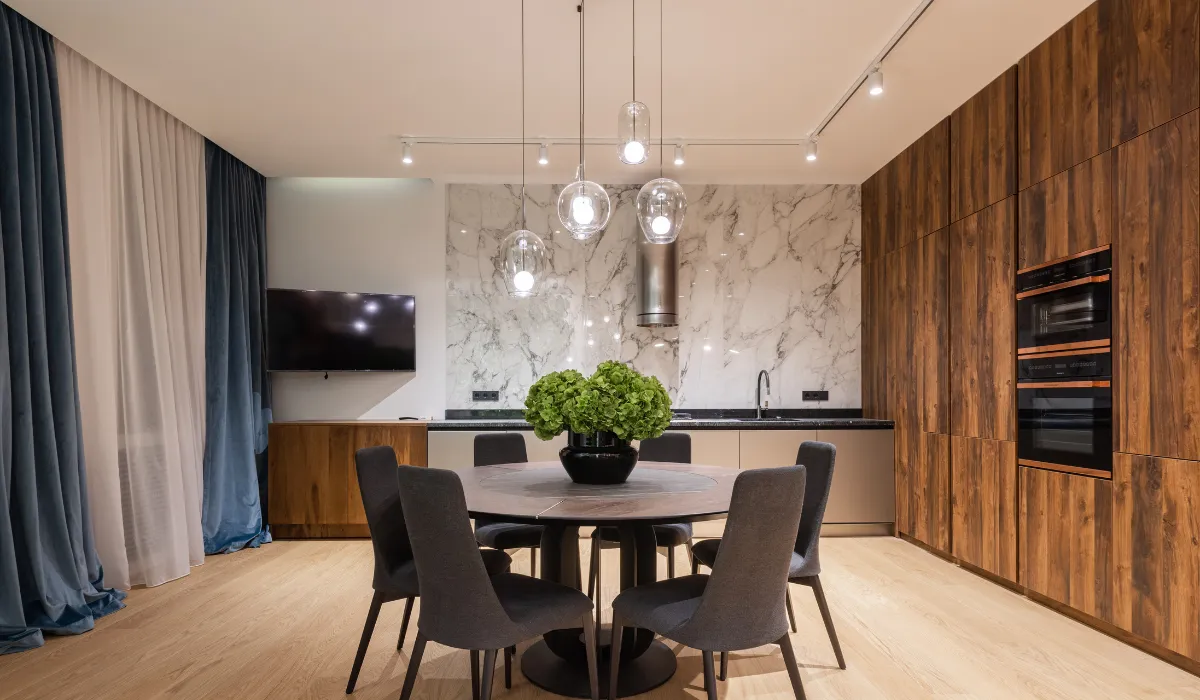 Modern dining area with pendant lights, marble backsplash, and wood panel cabinets. 