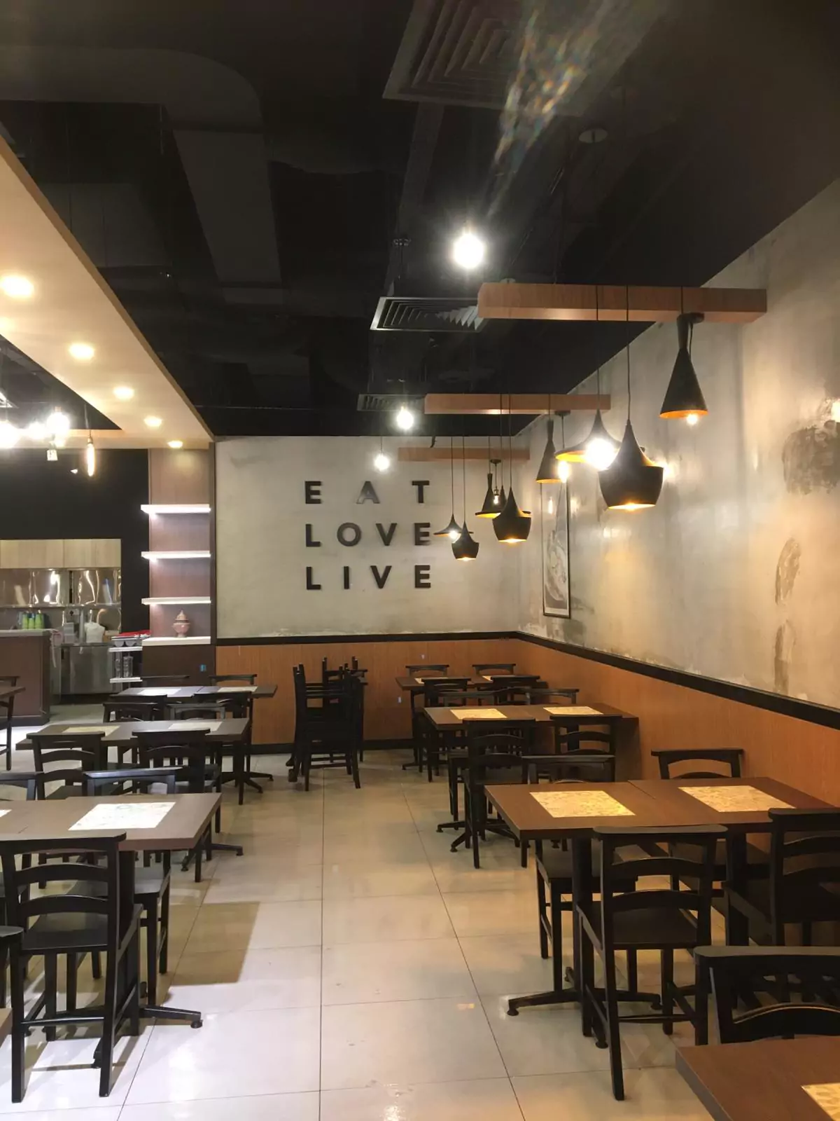 {"default":"Cozy downtown restaurant interior illuminated by modern pendant lights hanging over black dining tables."}
