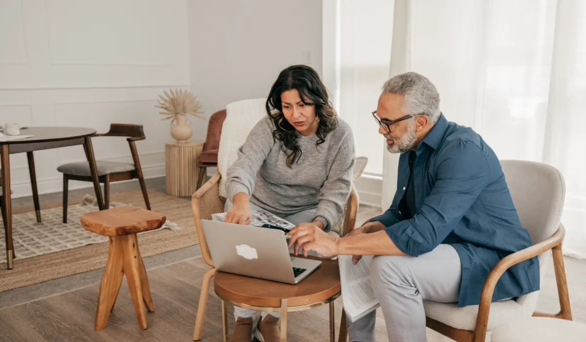An older couple reviewing information on a laptop while sitting in a modern living room.