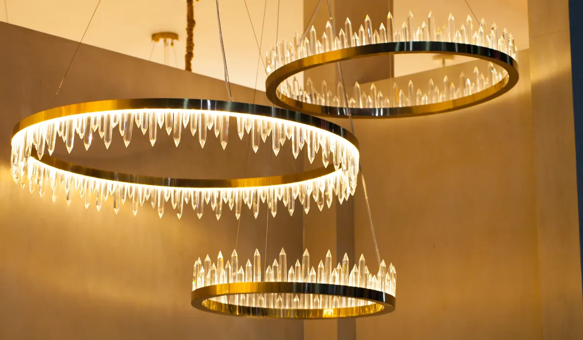 Close-up of modern crystal ring chandeliers with warm LED lighting in a stylish interior.