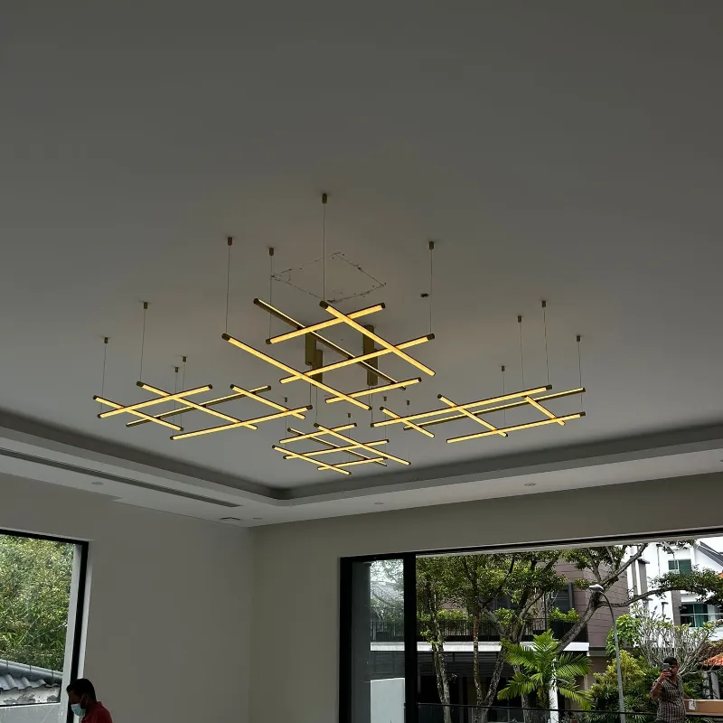 Modern geometric pendant light with gold accents suspended in a high-ceiling living space.