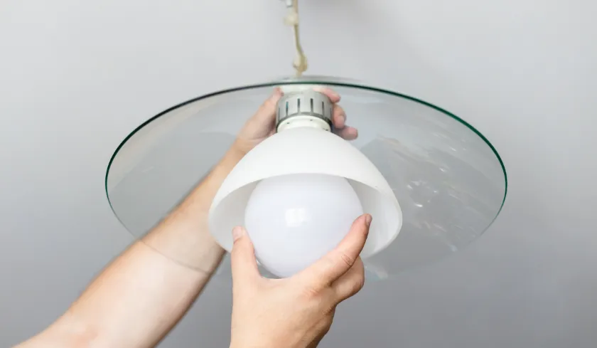 Hands installing a smart light bulb into a ceiling fixture