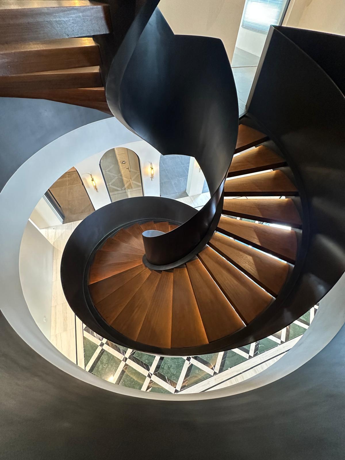Spiral staircase with soft lighting accentuating its sculptural curves.