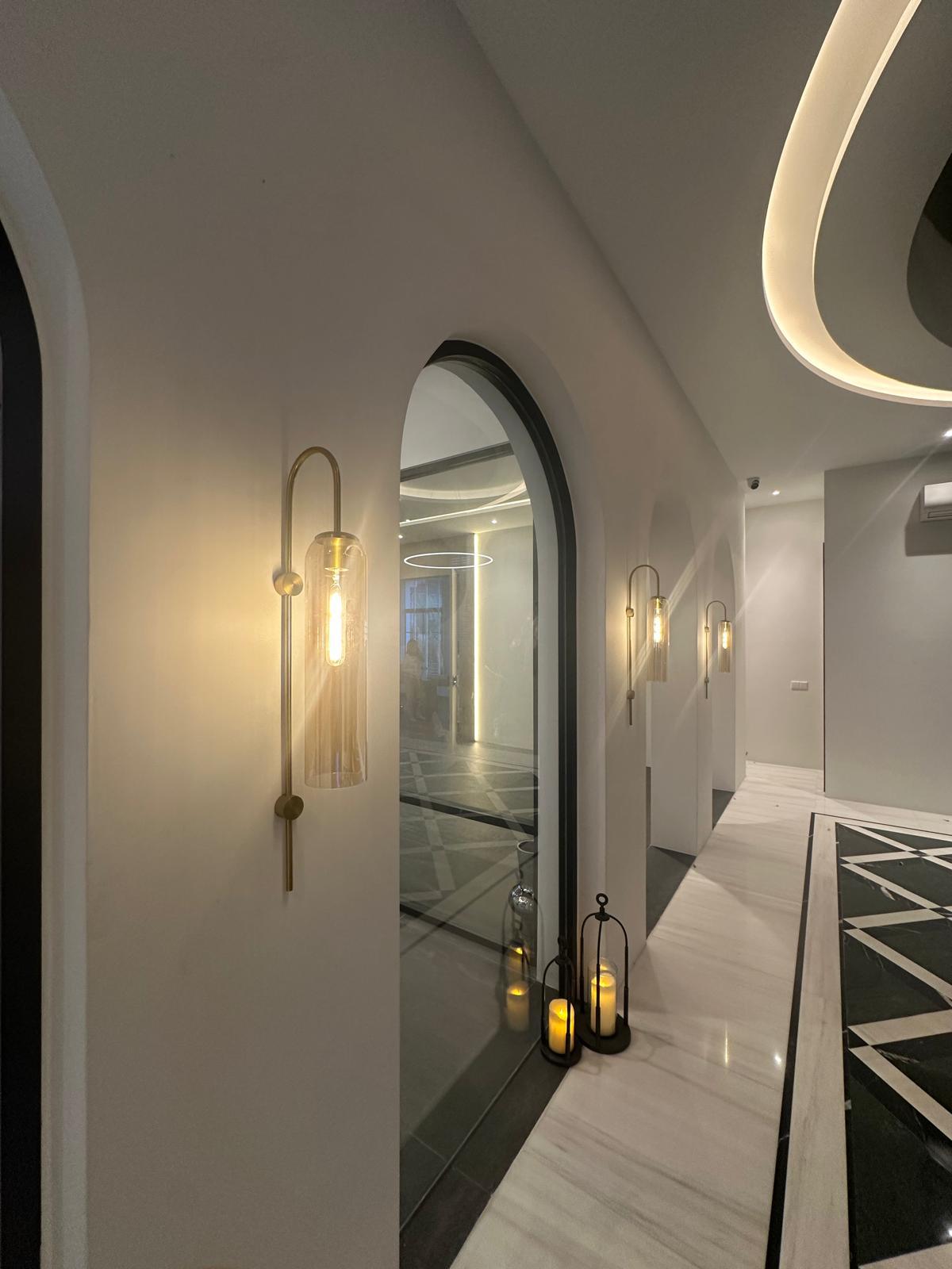 Interior hallway with gold wall sconces and warm ambient lighting.