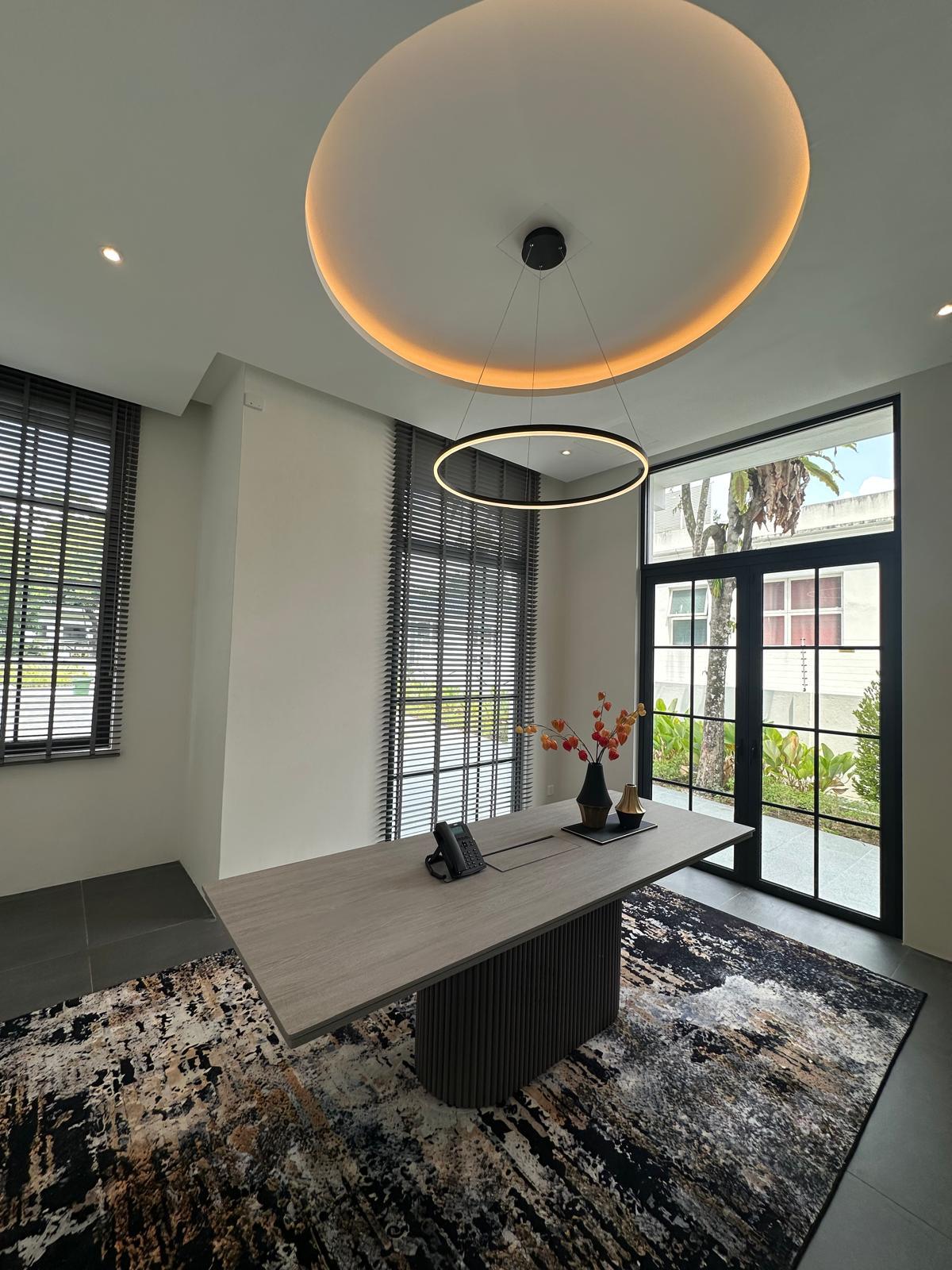 Modern study with ring pendant light and natural daylight through tall windows.