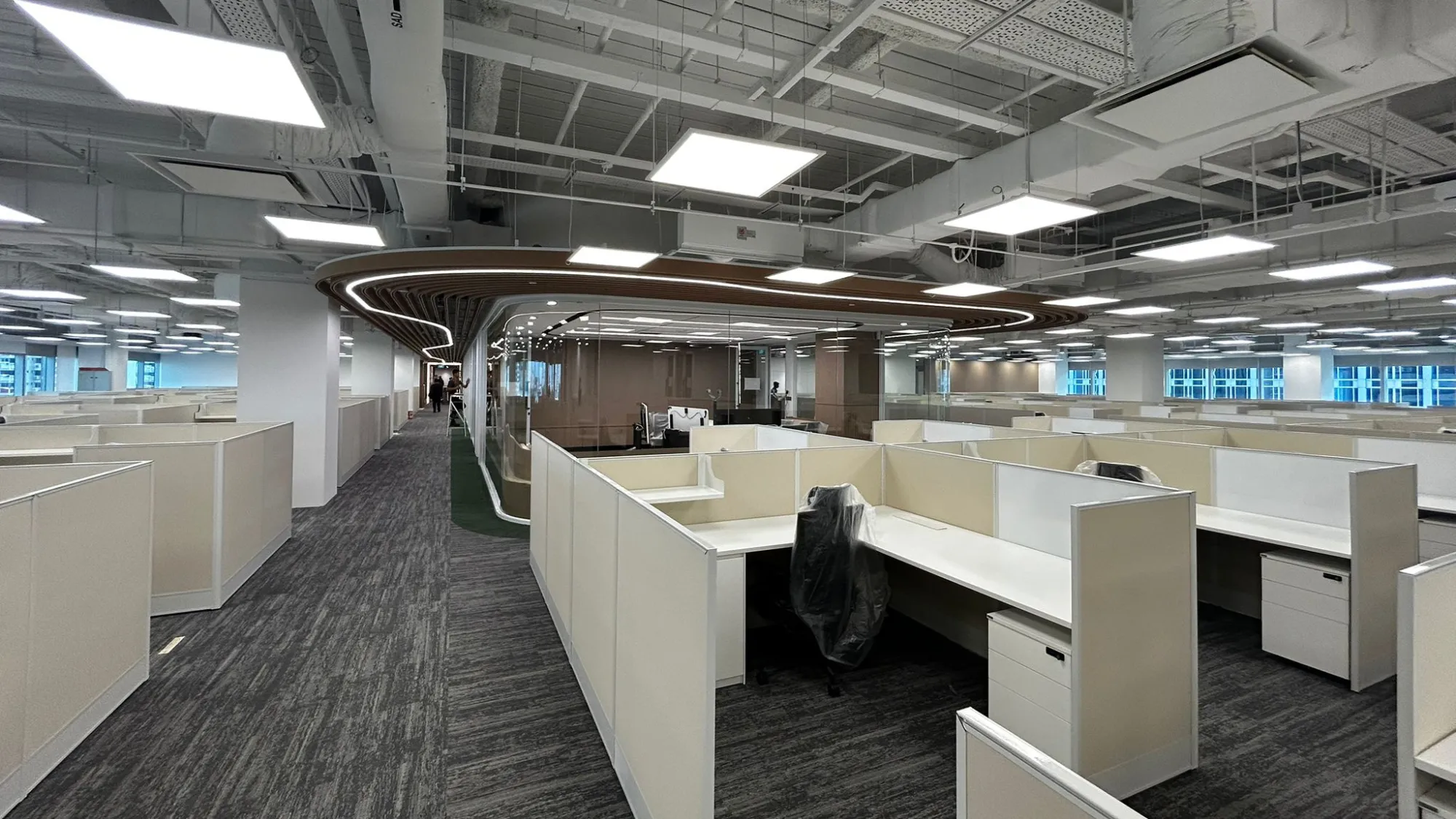 Open office layout with bright LED panels and curved architectural ceiling lighting.