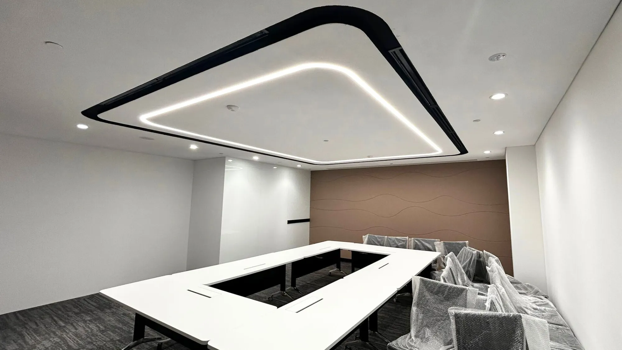 Boardroom with custom LED ceiling lighting and modern wave-textured feature wall.