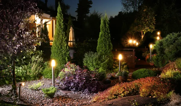 Outdoor garden with layered lighting illuminating paths and greenery