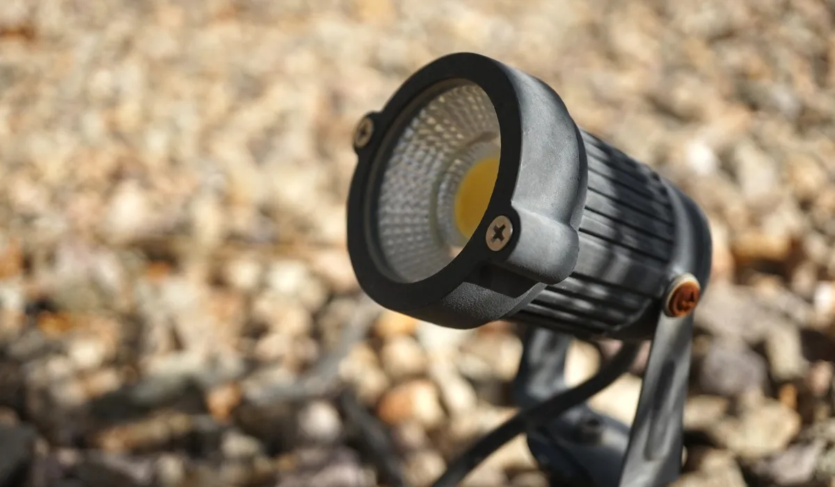 Close-up of outdoor spotlight fixture on gravel surface