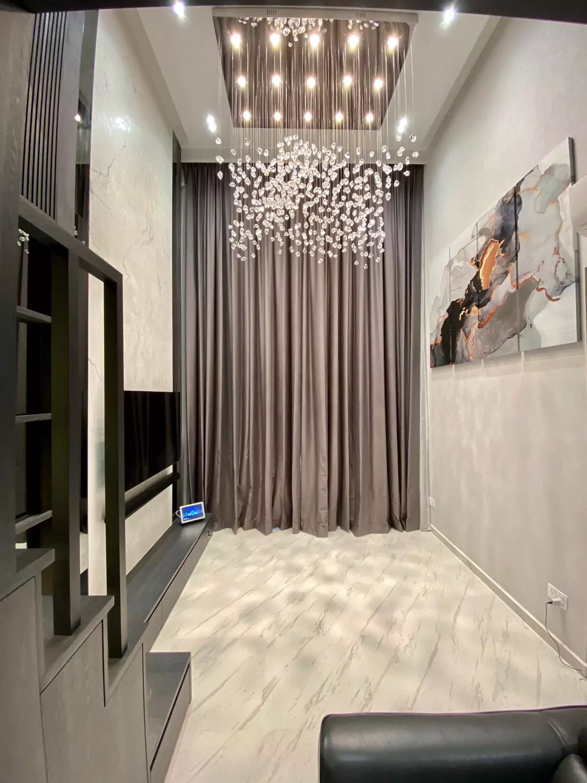 {"default":"Luxurious room featuring a grand sculptural chandelier made of numerous cascading crystal elements that create a dazzling effect, hanging over a marble-patterned floor."}