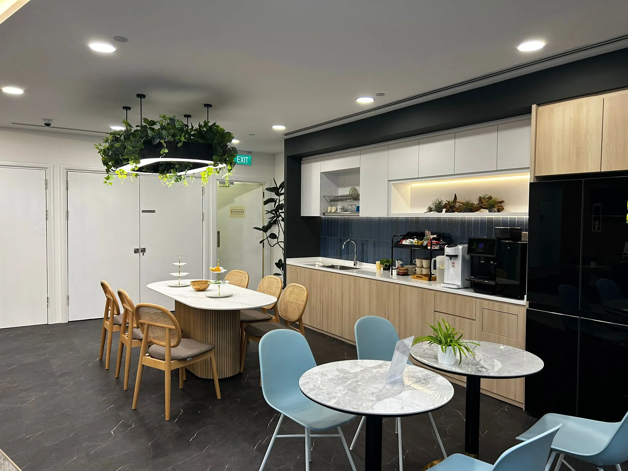 Modern office pantry with a hanging pendant light in shared workspace setting.