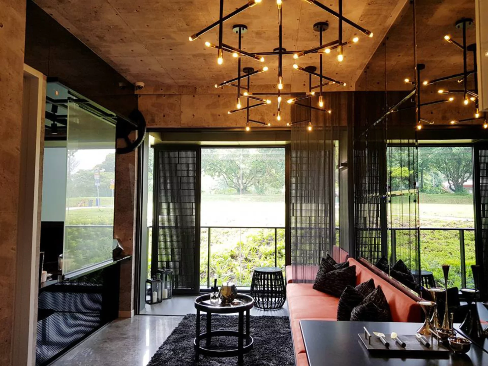 {"default":"Chic lounge area with contemporary design featuring unique ceiling-mounted light fixtures with multiple arms and exposed bulbs, set against a concrete ceiling. "}