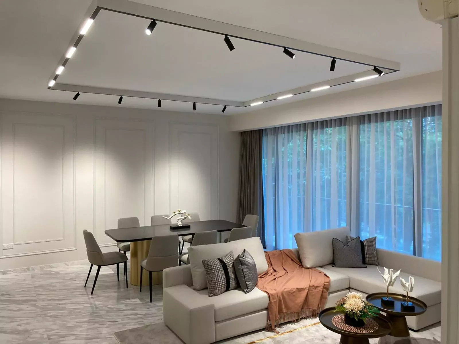 {"default":"Elegantly furnished showflat living and dining area illuminated by modern LED track lighting overhead. "}