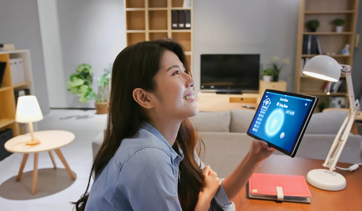 Smiling woman using tablet to control smart fan in living room