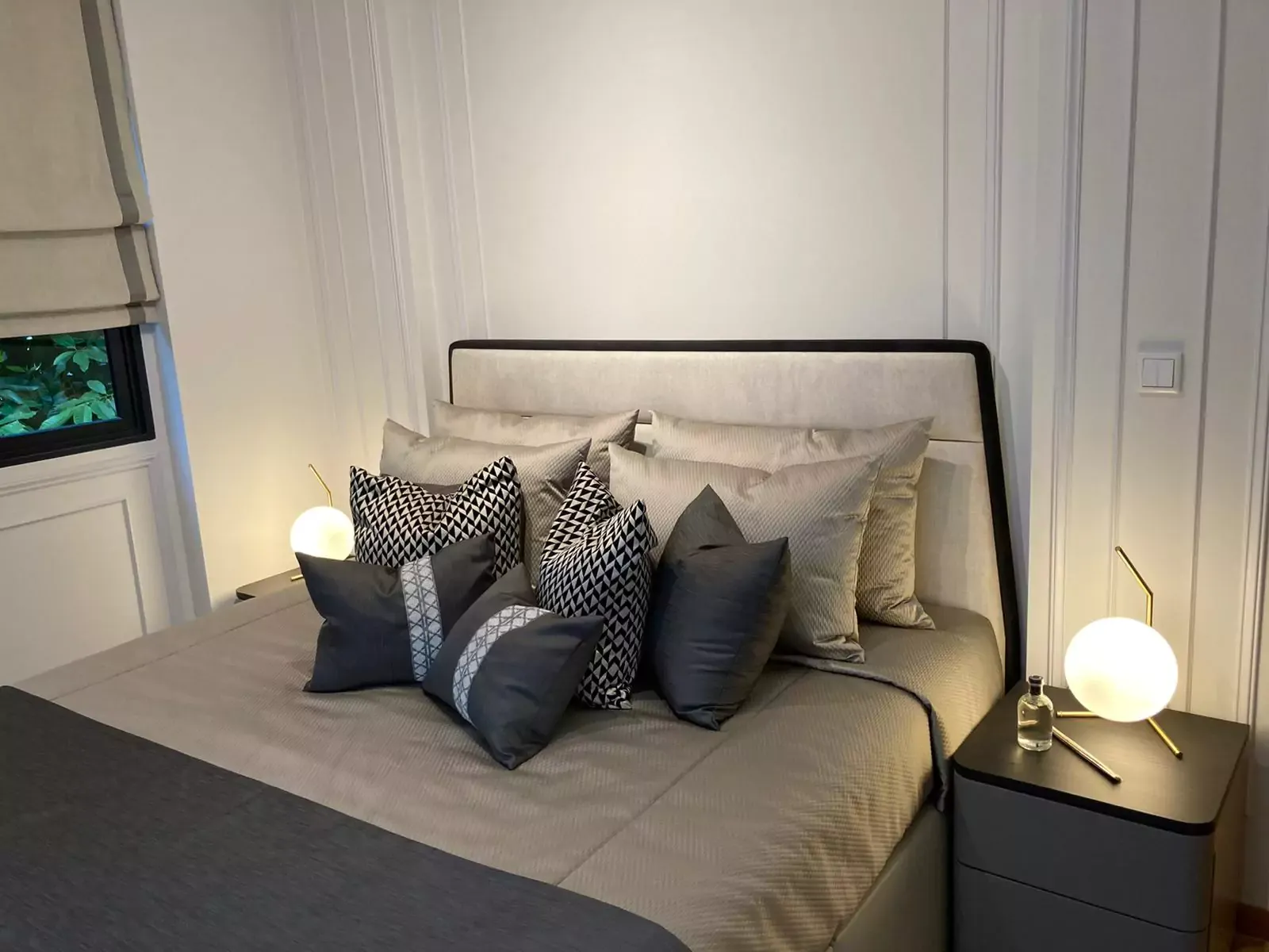 {"default":"Each side of the bed features a nightstand with a spherical white lamp, set against a paneled white wall, creating a warm and inviting atmosphere."}