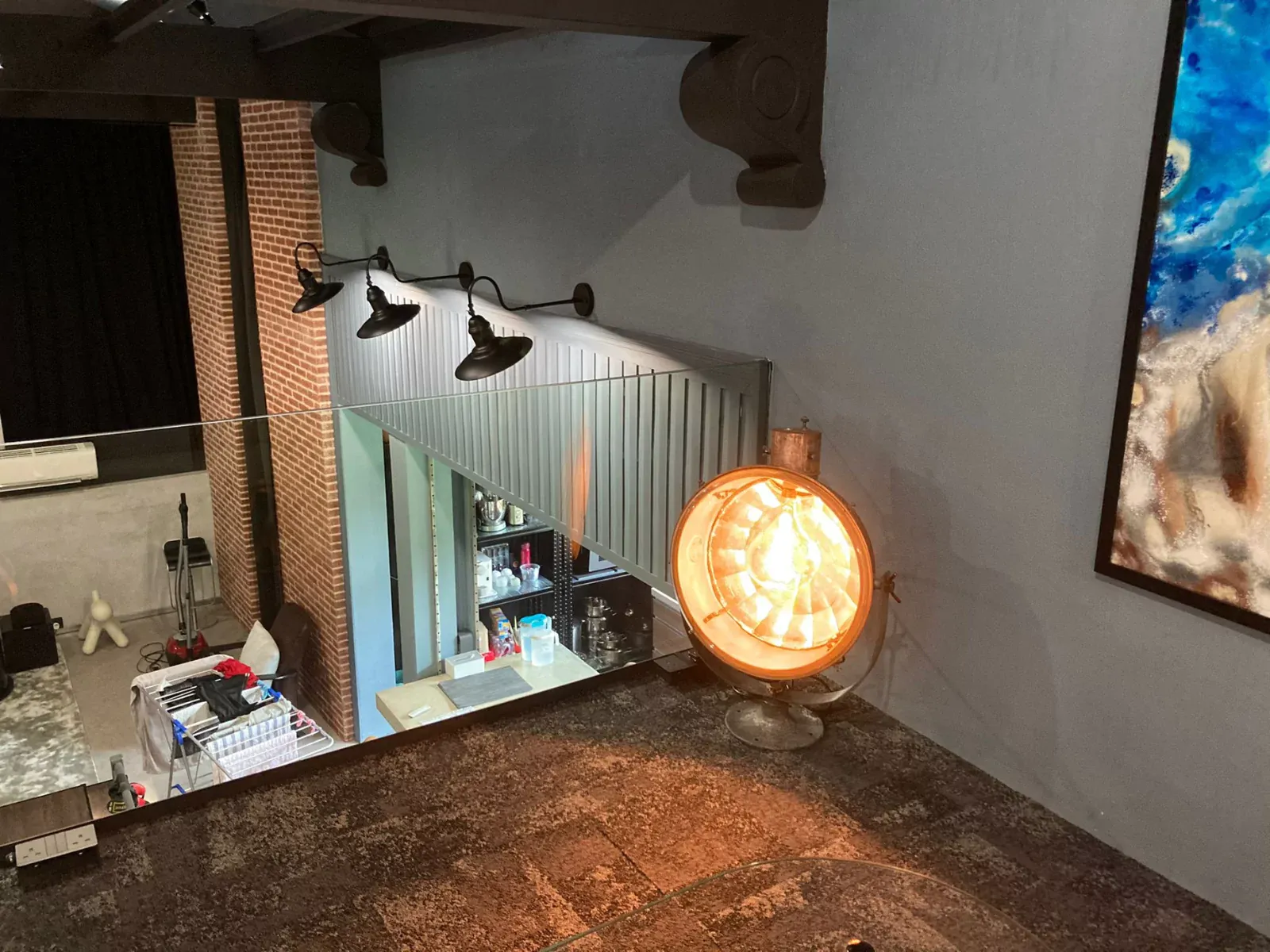 {"default":"Cozy corner of a room showcasing a vintage-style spherical light emitting a warm, orange glow, mounted on a rustic textured wall. Below it, a bar area with modern amenities is visible, creating a blend of old and new design elements."}