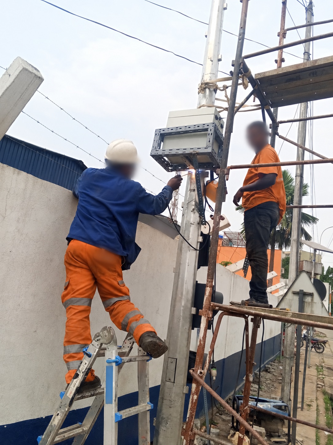 Workers installing pole-mounted equipment enclosures and brackets