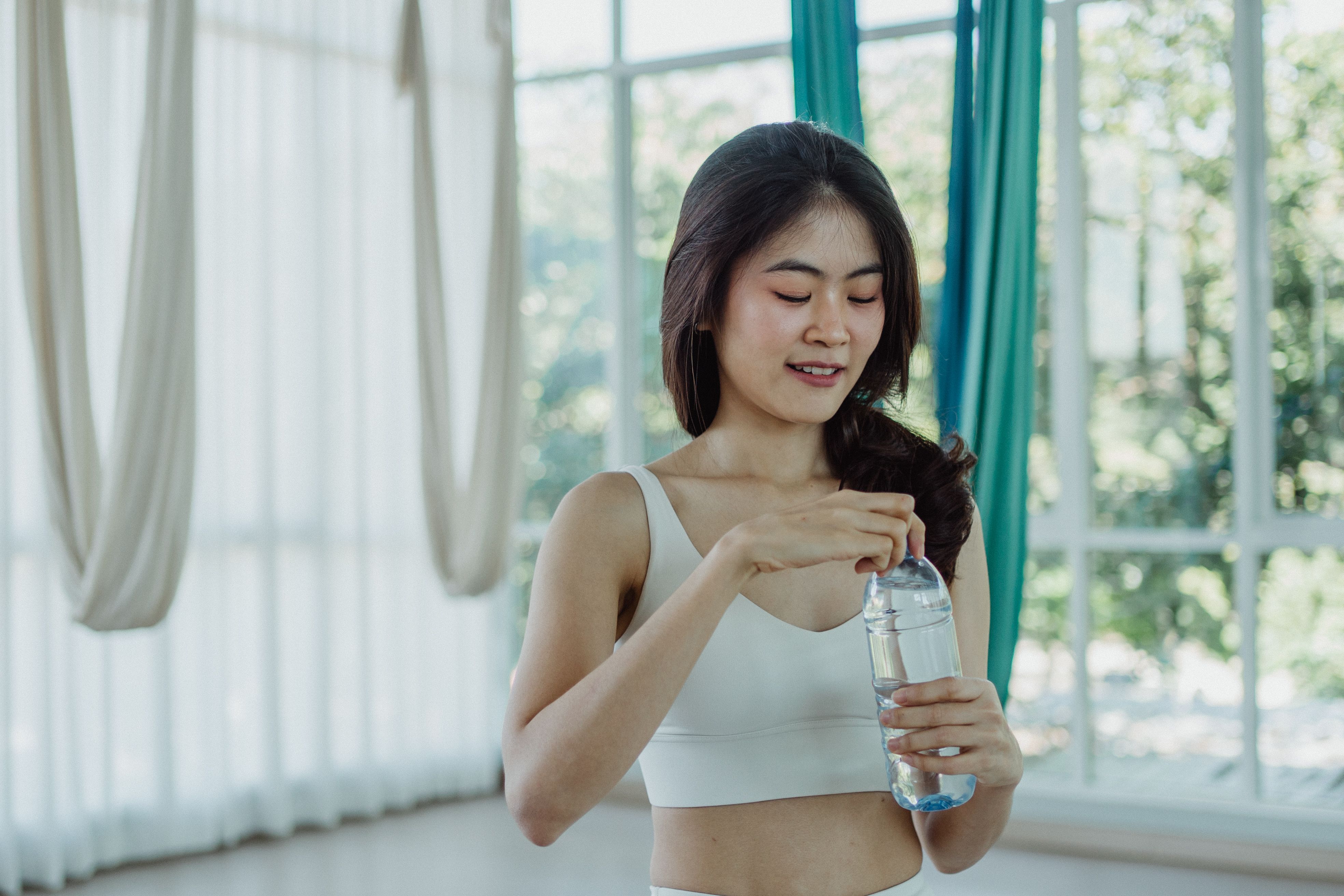 VEIMIA woman in sports bra taking a workout break in a bright studio