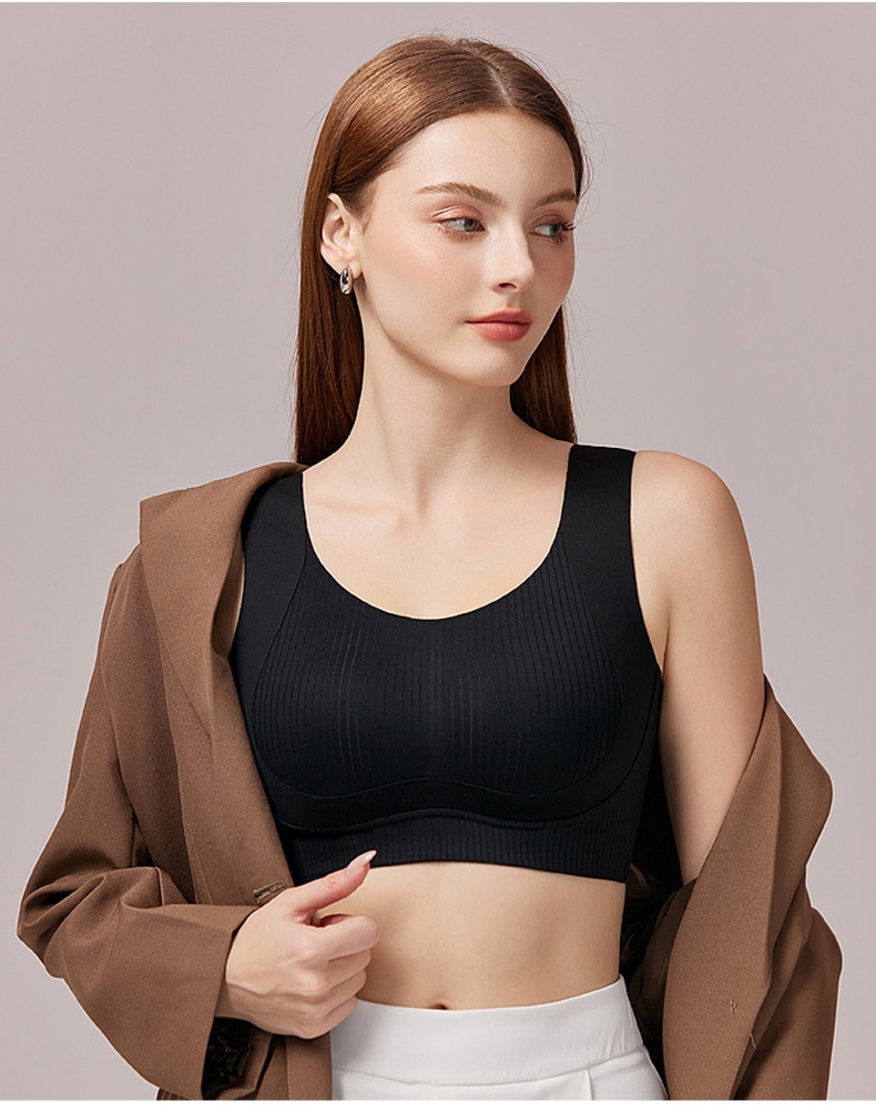 Model wearing black seamless bra under an open brown jacket VEIMIA