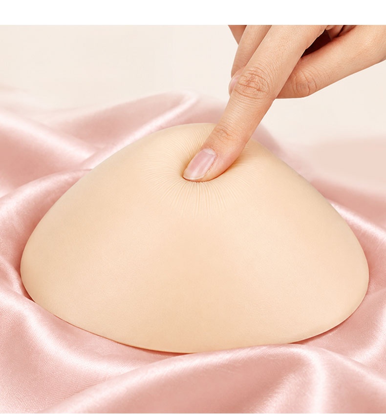 特寫鏡頭展示了用手指按壓的柔軟有彈性的乳房假體 VEIMIA