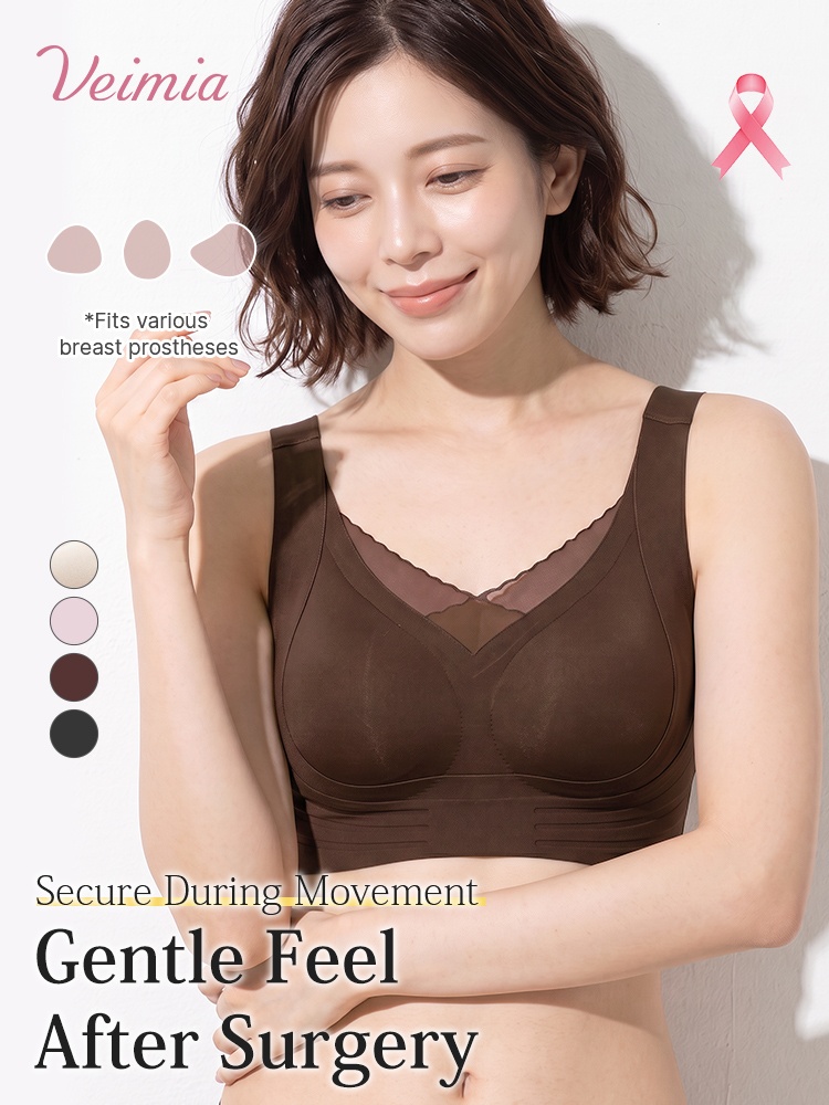 Model wearing brown mastectomy bra while holding a breast prosthesis VEIMIA