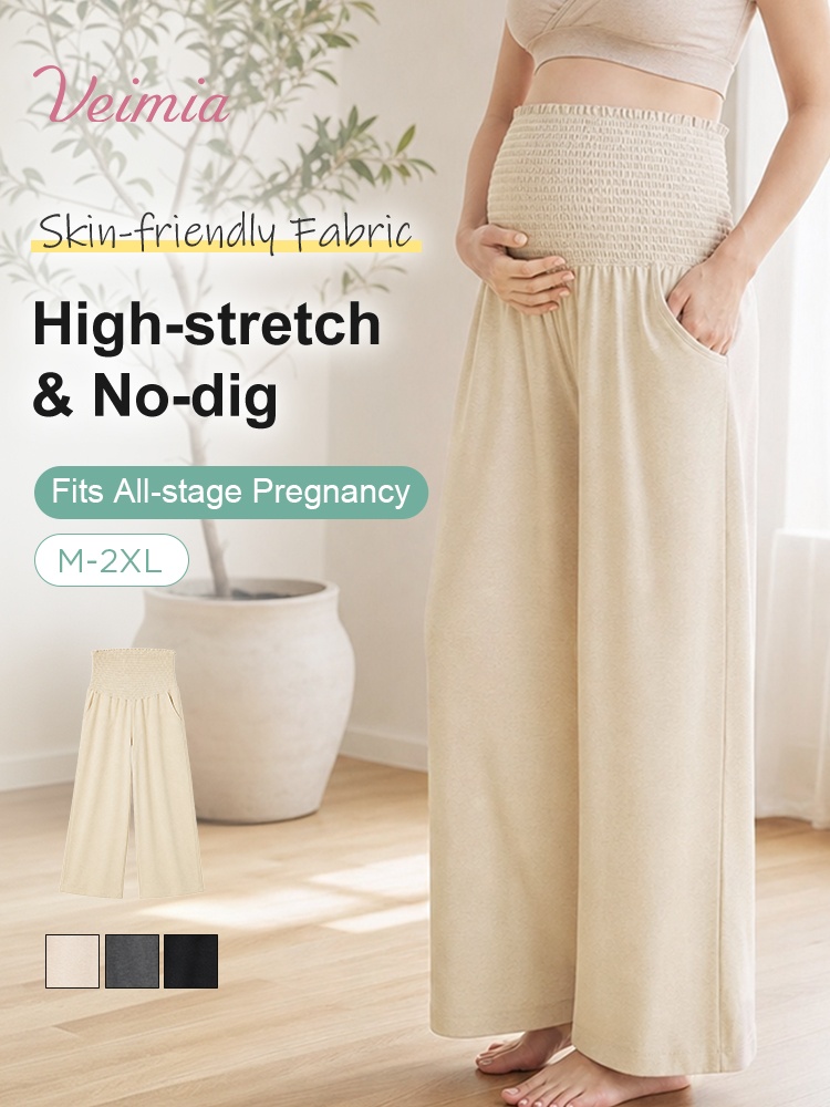 Model wearing beige high-waist maternity pants with wide legs and stretch belly panel VEIMIA