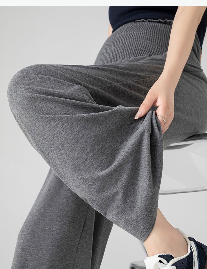 Close-up of gray maternity pants showing relaxed wide-leg drape while seated VEIMIA