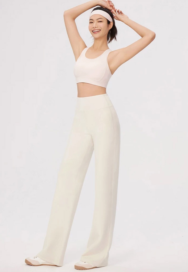 Smiling model wearing white straight-cut pants with active styling VEIMIA