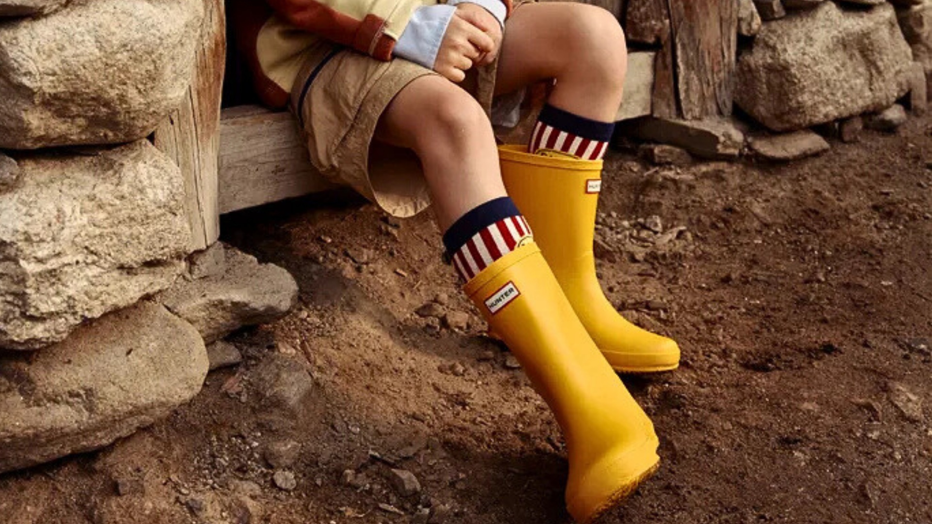 Close-up of navy and yellow Hunter kids' rain boots in Malaysia with a rainbow patch detail.
