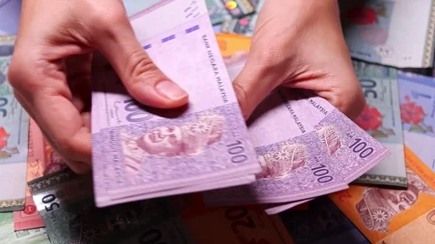Womans hands counting brand new Malaysian ringgit (MYR) banknotes