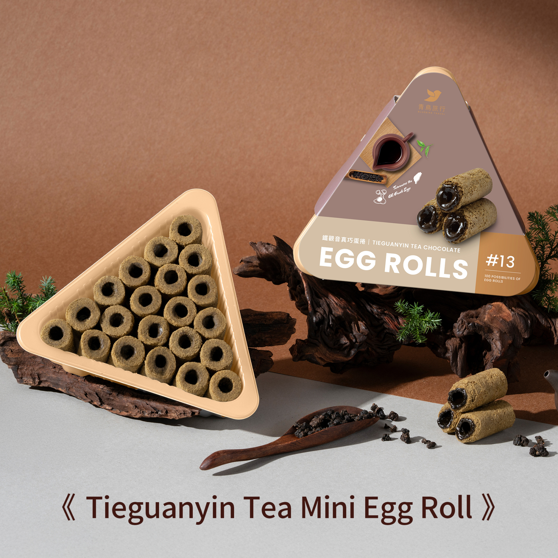 Tieguanyin tea chocolate mini egg rolls in open triangular share box with tea leaves and wooden props.