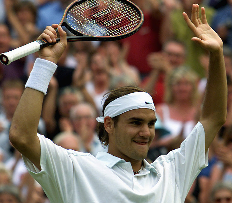 Roger Federer, hands raised above his head, seemingly celebrating