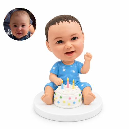 custom bobblehead figure baby sitting behind a decorated birthday cake