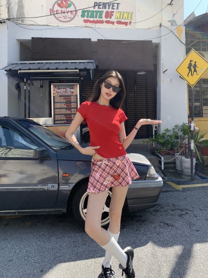 A short red plaid ruffle skirt with a high-low design, featuring a shorter front and longer back, styled for a sexy summer look.