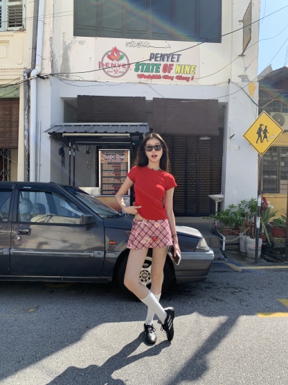 A short red plaid ruffle skirt with a high-low design, featuring a shorter front and longer back, styled for a sexy summer look.