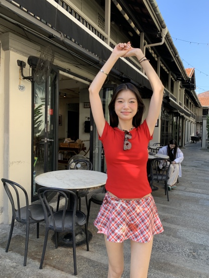 A short red plaid ruffle skirt with a high-low design, featuring a shorter front and longer back, styled for a sexy summer look.
