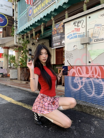 A short red plaid ruffle skirt with a high-low design, featuring a shorter front and longer back, styled for a sexy summer look.