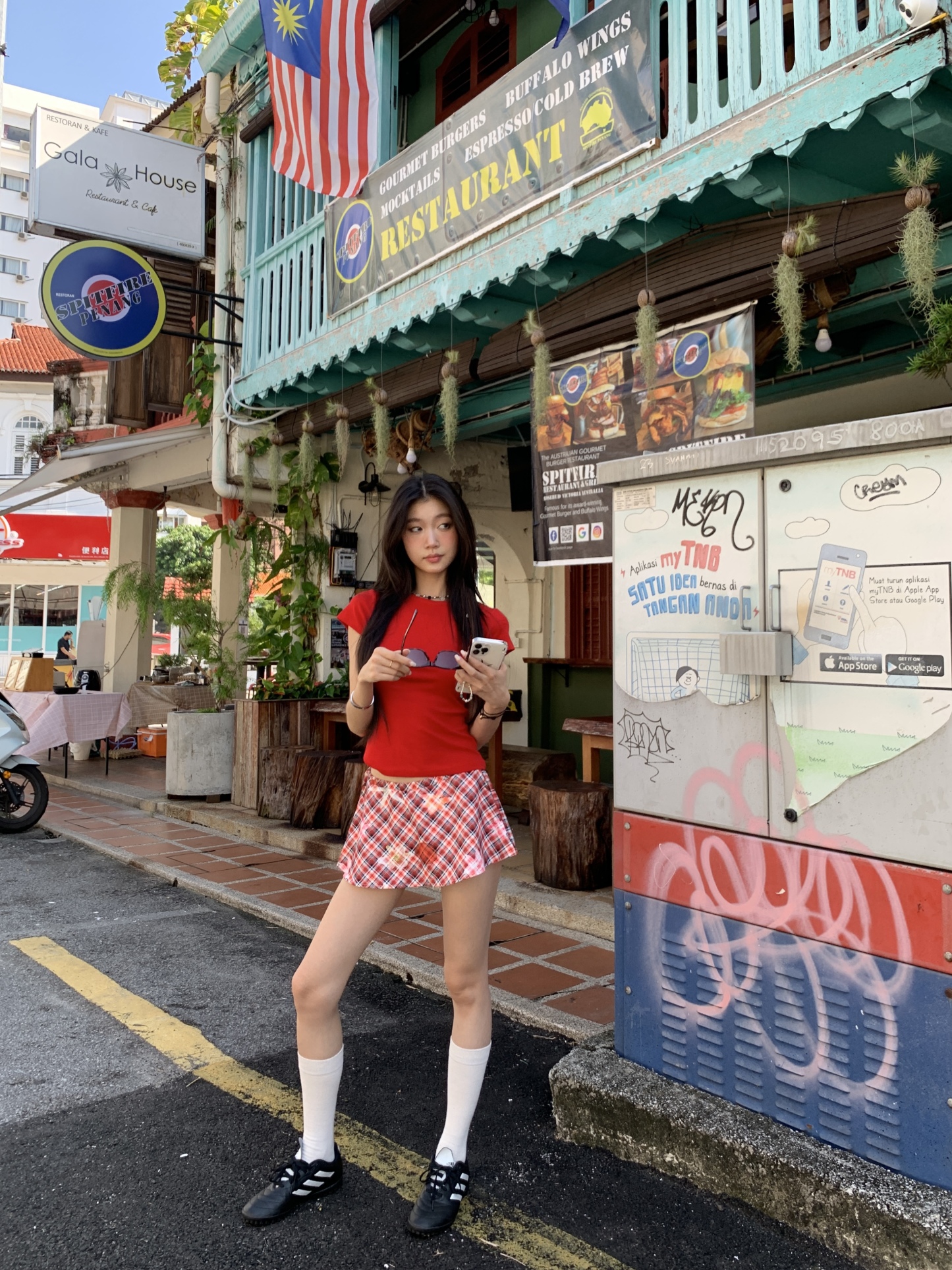 A short red plaid ruffle skirt with a high-low design, featuring a shorter front and longer back, styled for a sexy summer look.