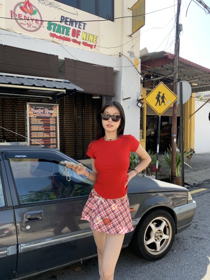 A short red plaid ruffle skirt with a high-low design, featuring a shorter front and longer back, styled for a sexy summer look.