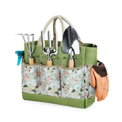 A green and floral canvas gardening tote bag organized with hand tools and gloves hanging on the side.