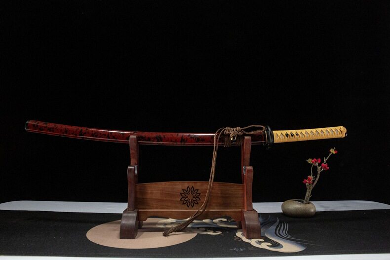 Handmade Rurouni Kenshin katana resting horizontally on a decorative stand against a black background.